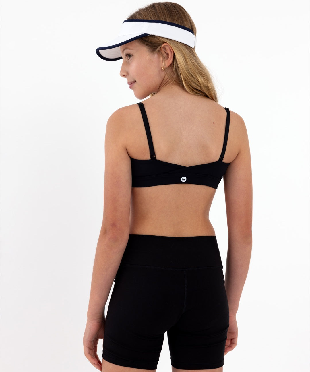Girl wearing a black SASSH Active sports bra for tweens, front view showing scoop neckline and adjustable straps — girls sports bra, first bra.