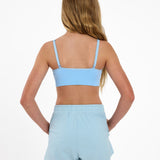 Back view of a girl wearing a light blue SASSH Essential training bra showing adjustable criss-cross straps — girls first bra, seamless training bra.
