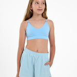 Girl wearing a light blue SASSH Essential training bra with seamless underband, front view — girls first bra for tweens.