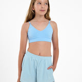 Girl wearing a light blue SASSH Essential training bra with seamless underband, front view — girls first bra for tweens.
