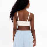 Back view of a girl wearing a white SASSH Essential training bra showing adjustable criss-cross straps — girls first bra, seamless training bra.