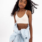 Girl wearing a white SASSH Essential training bra with seamless underband, front view — girls first bra for tweens.