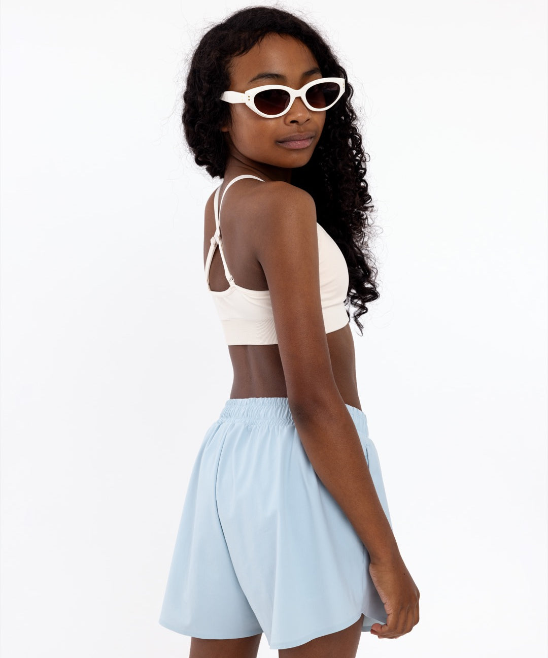 Side view of a girl wearing a white SASSH Essential training bra showing seamless crop top fit — girls seamless training bra, first bra.