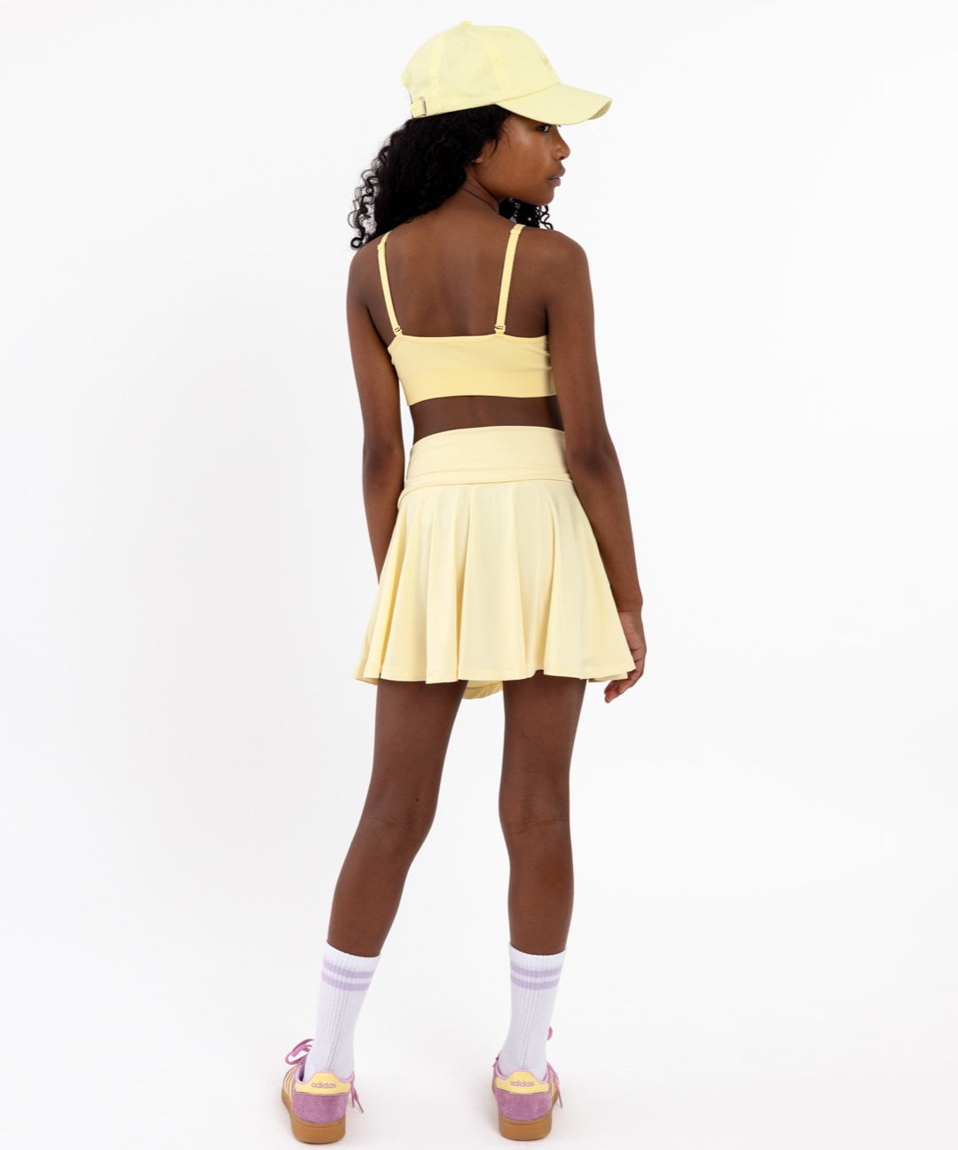 Back view of a girl wearing a lemon yellow SASSH Essential training bra showing adjustable criss-cross straps — girls first bra, seamless training bra.
