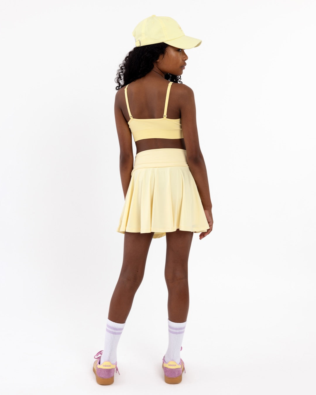 Back view of a girl wearing a lemon yellow SASSH Essential training bra showing adjustable criss-cross straps — girls first bra, seamless training bra.