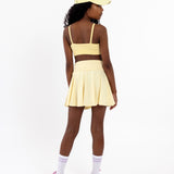Back view of a girl wearing a lemon yellow SASSH Essential training bra showing adjustable criss-cross straps — girls first bra, seamless training bra.
