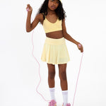 Girl wearing a lemon yellow SASSH Essential training bra in a complete outfit — first bra for tweens and teens.