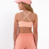 Close-up back view of a peach SASSH Essential training bra showing adjustable criss-cross straps and seamless underband — girls first bra.