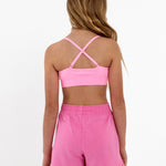 Back view of a girl wearing a bright pink SASSH Essential training bra showing adjustable criss-cross straps — girls first bra, seamless training bra.