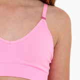 Close-up of a bright pink SASSH Essential training bra showing bow strap detail and seamless underband — girls seamless training bra, first bra.