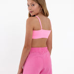 Side view of a girl wearing a bright pink SASSH Essential training bra showing seamless crop top fit — girls training bra, first bra.