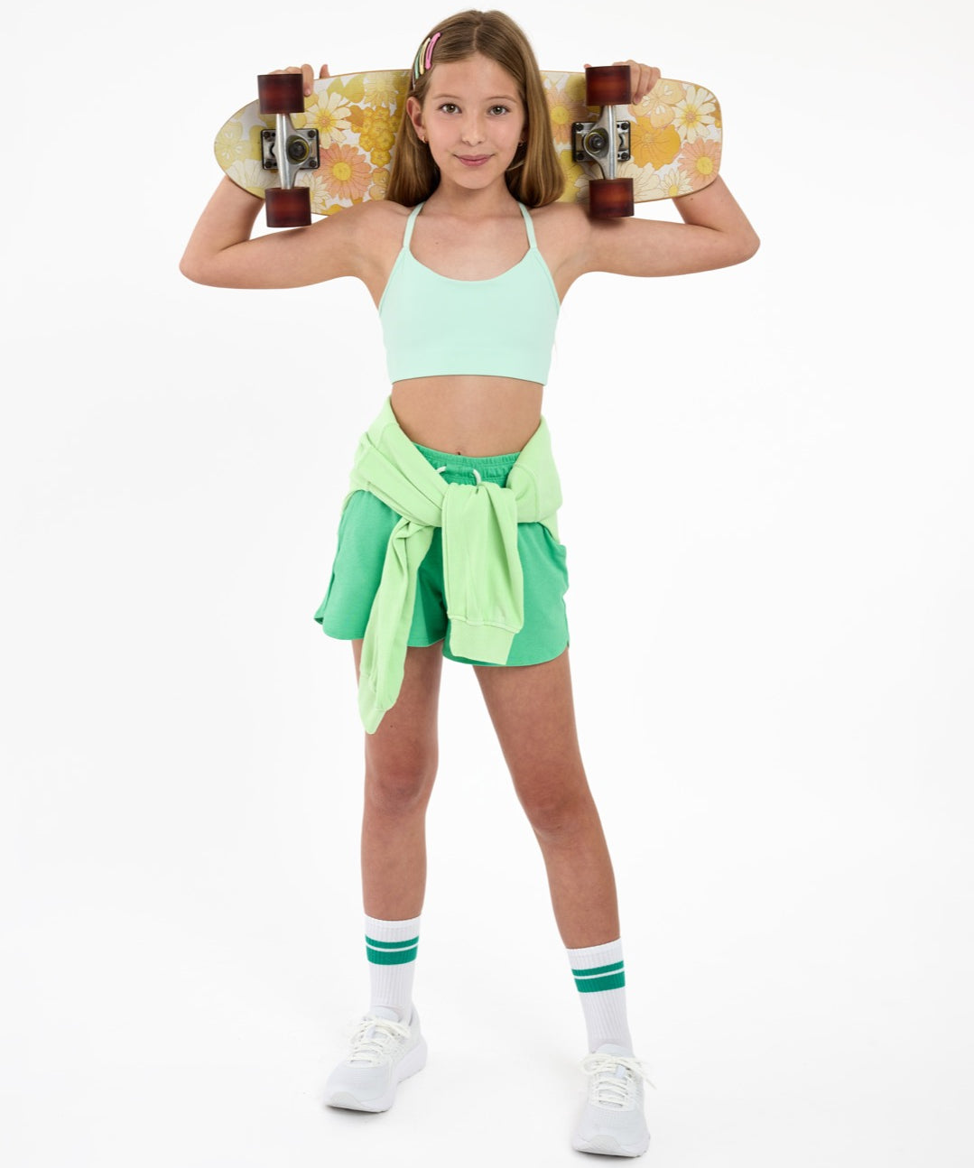 Girl wearing a mint green SASSH The Energy sports bra styled in an outfit on a white background — tween girls sports bra.