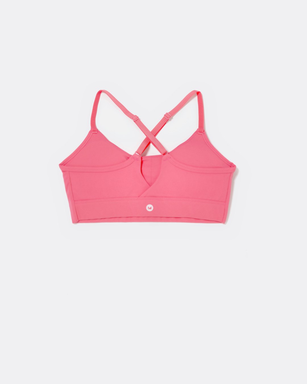SASSH The Energy sports bra in hot pink, back ghost view, showing crossover racerback strap detail — girls sports bra, first sports bra.
