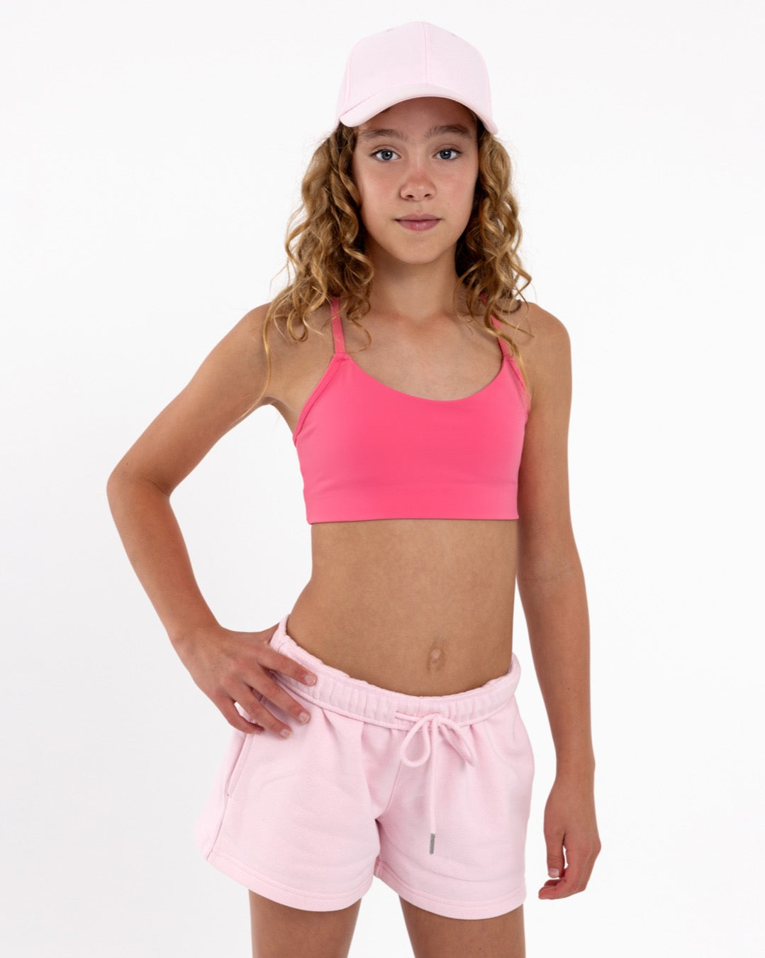 Girl wearing a hot pink SASSH The Energy sports bra with seamless underband, front view — first sports bra for tweens.