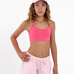 Girl wearing a hot pink SASSH The Energy sports bra with seamless underband, front view — first sports bra for tweens.