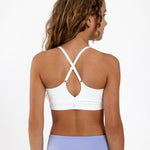 Back view of a girl wearing a white SASSH The Energy sports bra showing crossover racerback strap detail — girls sports bra.