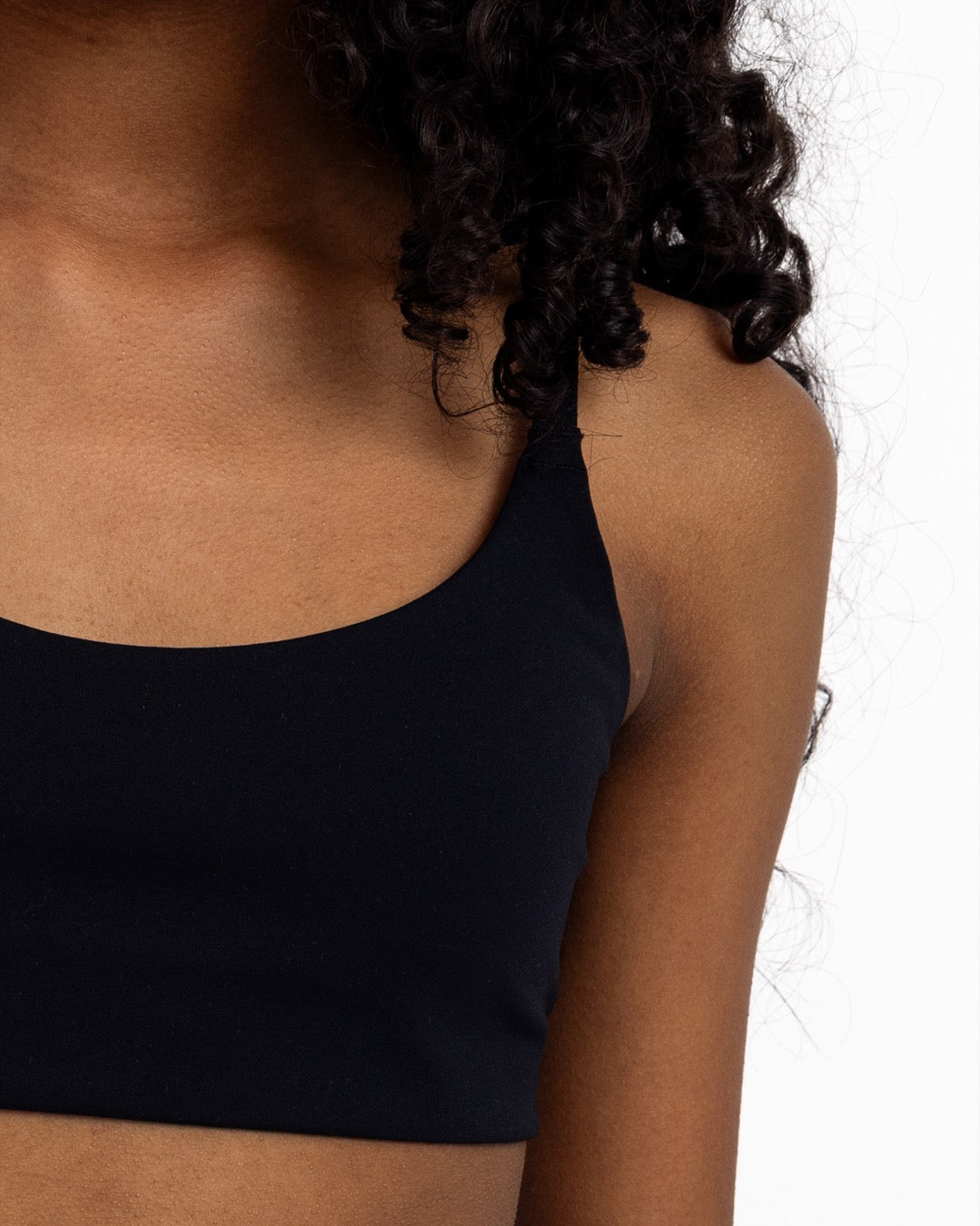 Close-up of a girl wearing a black sports bra with adjustable straps, and a pullover style.