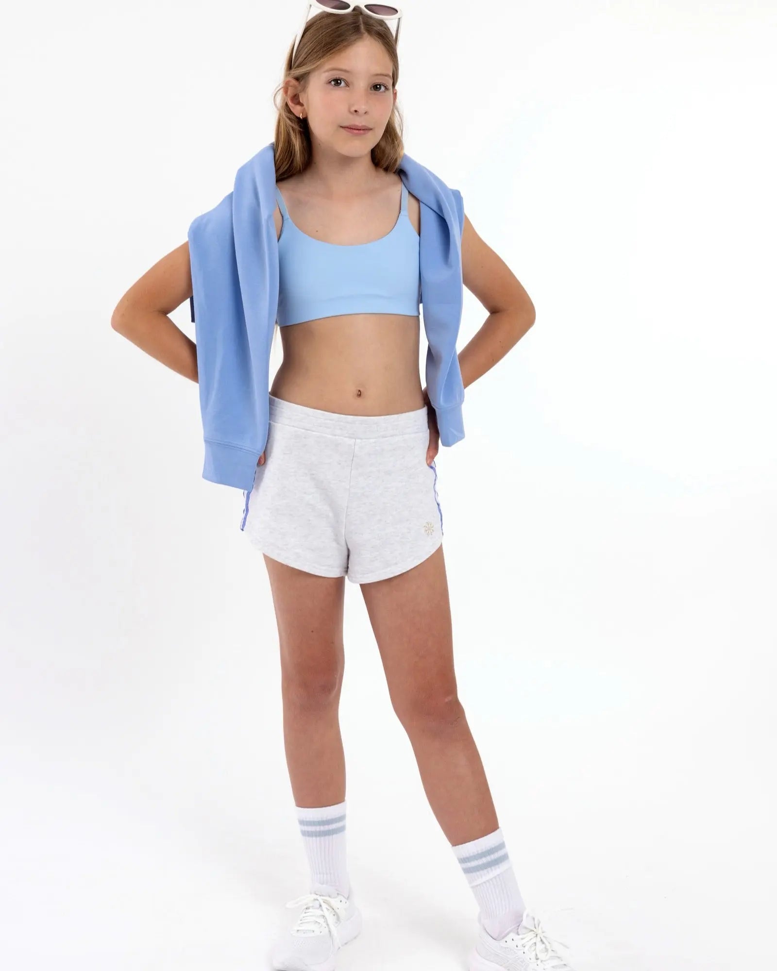 Girl wearing a light blue first scoop sports bra with adjustable straps, and a pullover style.