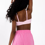 Back view of a girl wearing a pink sports bra with adjustable straps, and a pullover style in a white background.