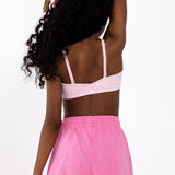 Back view of a girl wearing a pink sports bra with adjustable straps, and a pullover style in a white background.