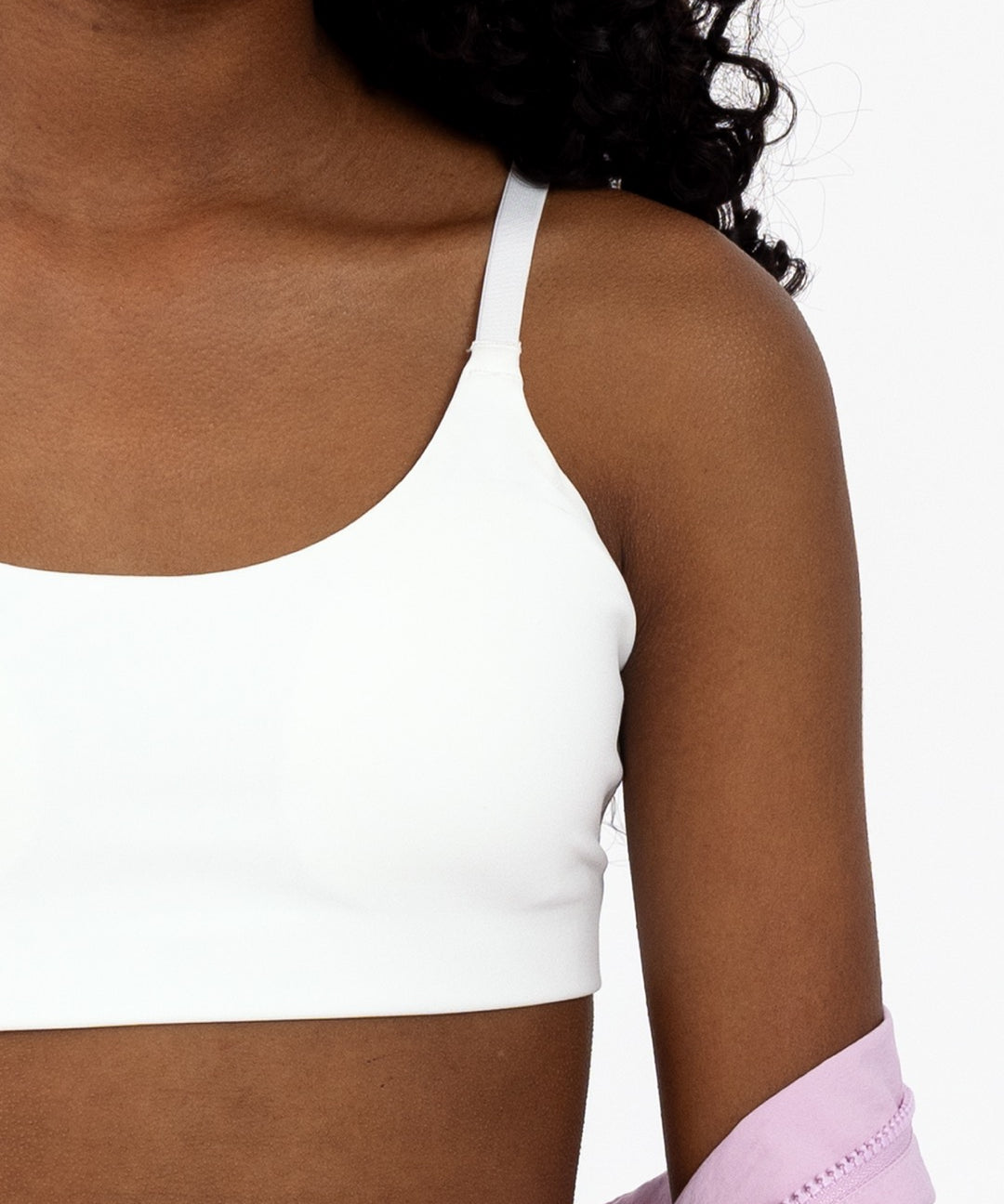 Close-up of a tween girl wearing a white scoop sports bra with adjustable straps and pullover style.