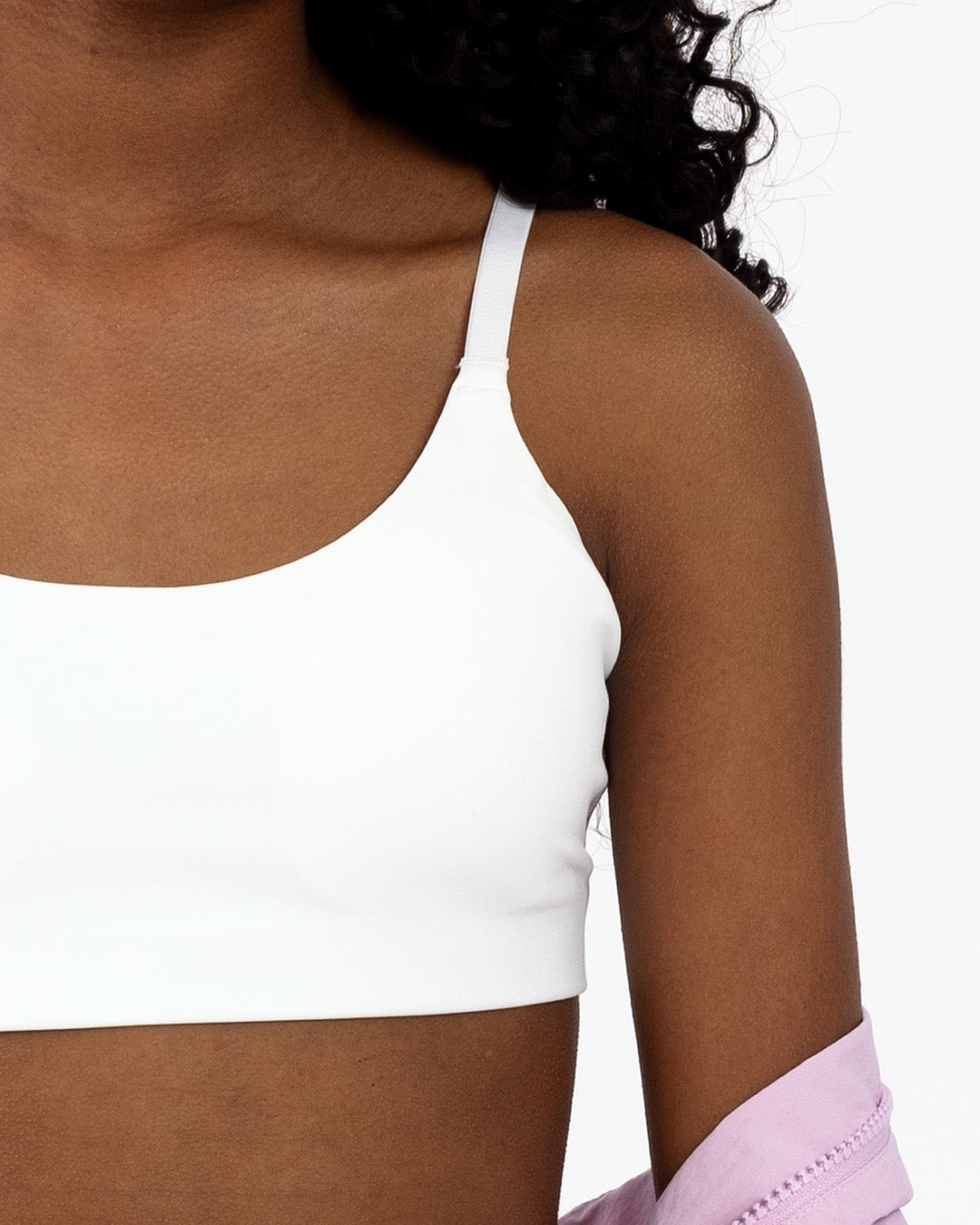 Close-up of a tween girl wearing a white scoop sports bra with adjustable straps and pullover style.