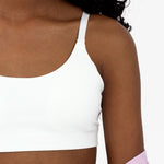Close-up of a tween girl wearing a white scoop sports bra with adjustable straps and pullover style.