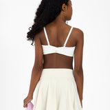 Back view of a girl wearing a white sports bra, holding a pink jacket on a white background.