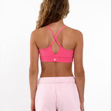 Back view of a girl wearing a hot pink longline sports bra showing crossover racerback detail and adjustable straps.