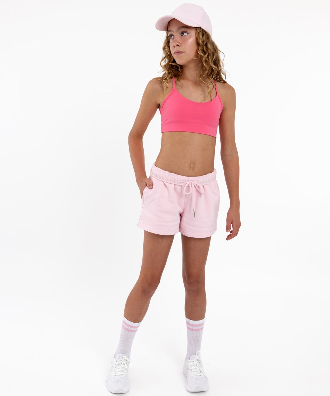 Girl wearing a hot pink longline sports bra showing smooth scoop neckline and a seamless underband on a white background.