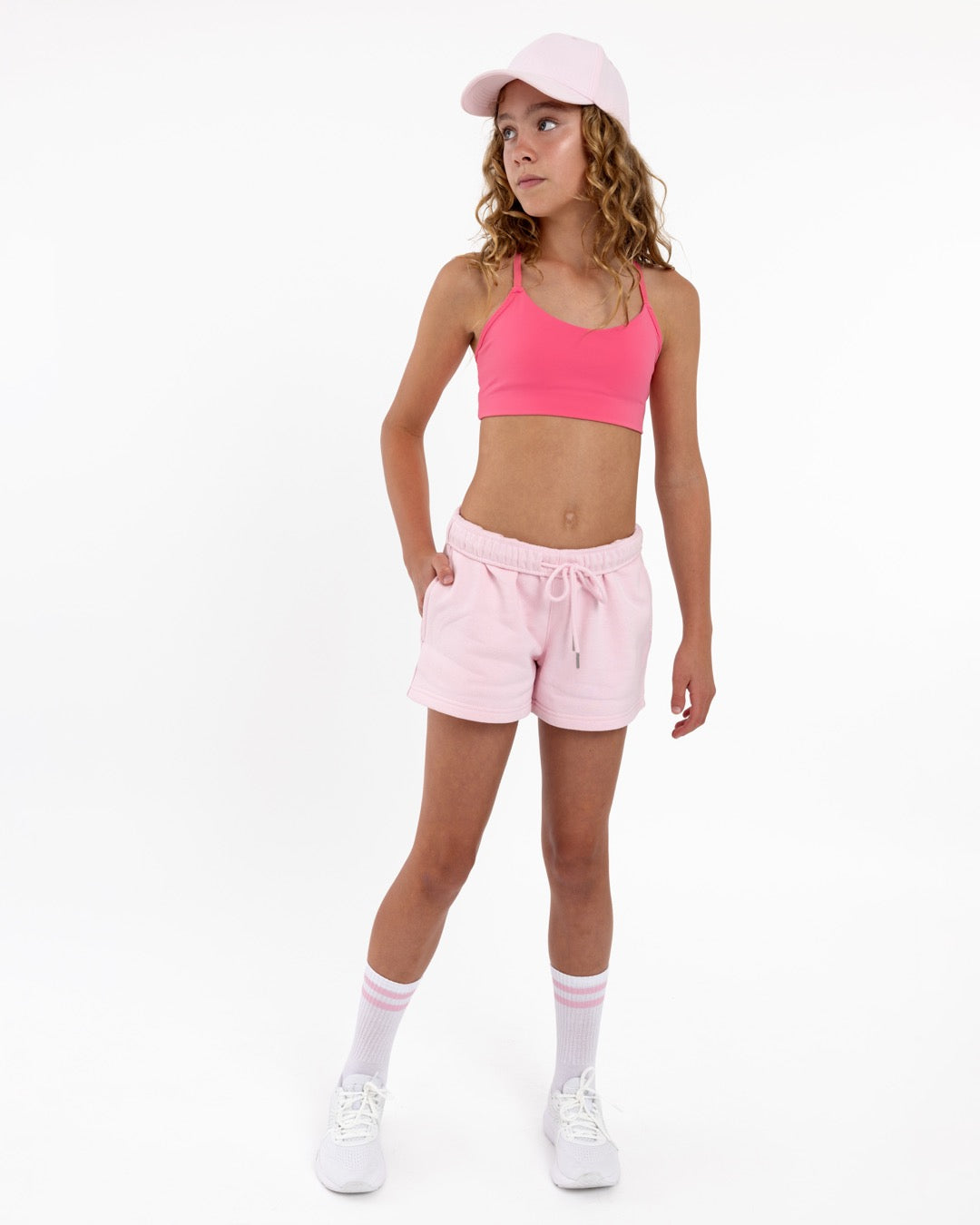 Girl wearing a hot pink longline sports bra showing smooth scoop neckline and a seamless underband on a white background.
