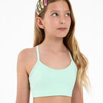 Girl wearing a mint green sports bra, with colourful hair clips  on a white background.