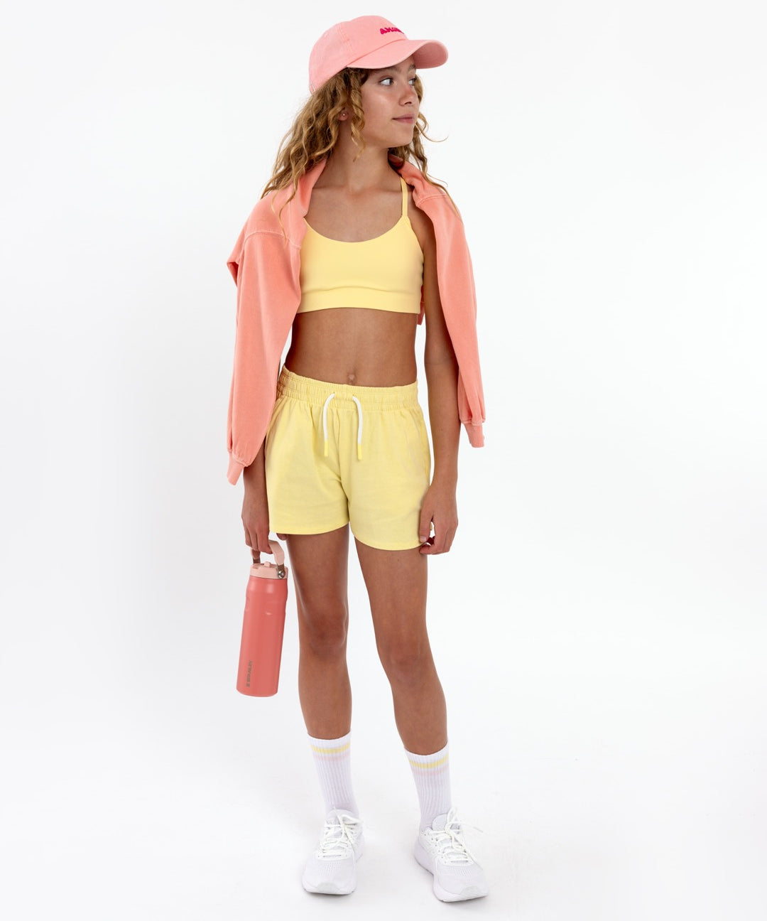 Girl wearing a yellow longline sports bra showing smooth scoop neckline and a seamless underband on a white background.