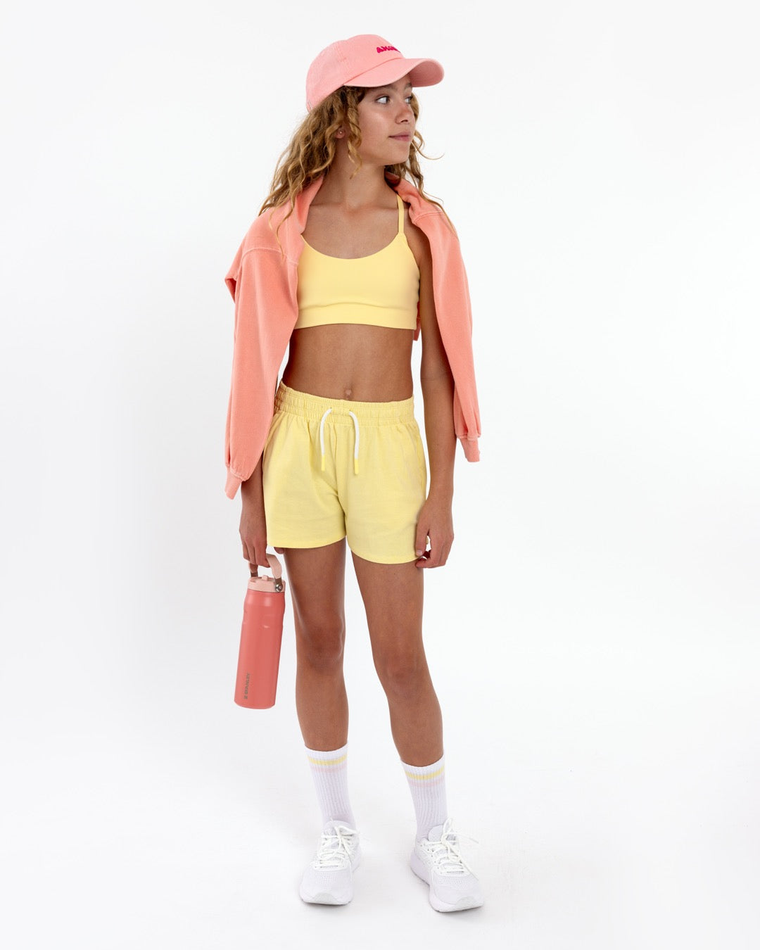 Girl wearing a yellow longline sports bra showing smooth scoop neckline and a seamless underband on a white background.
