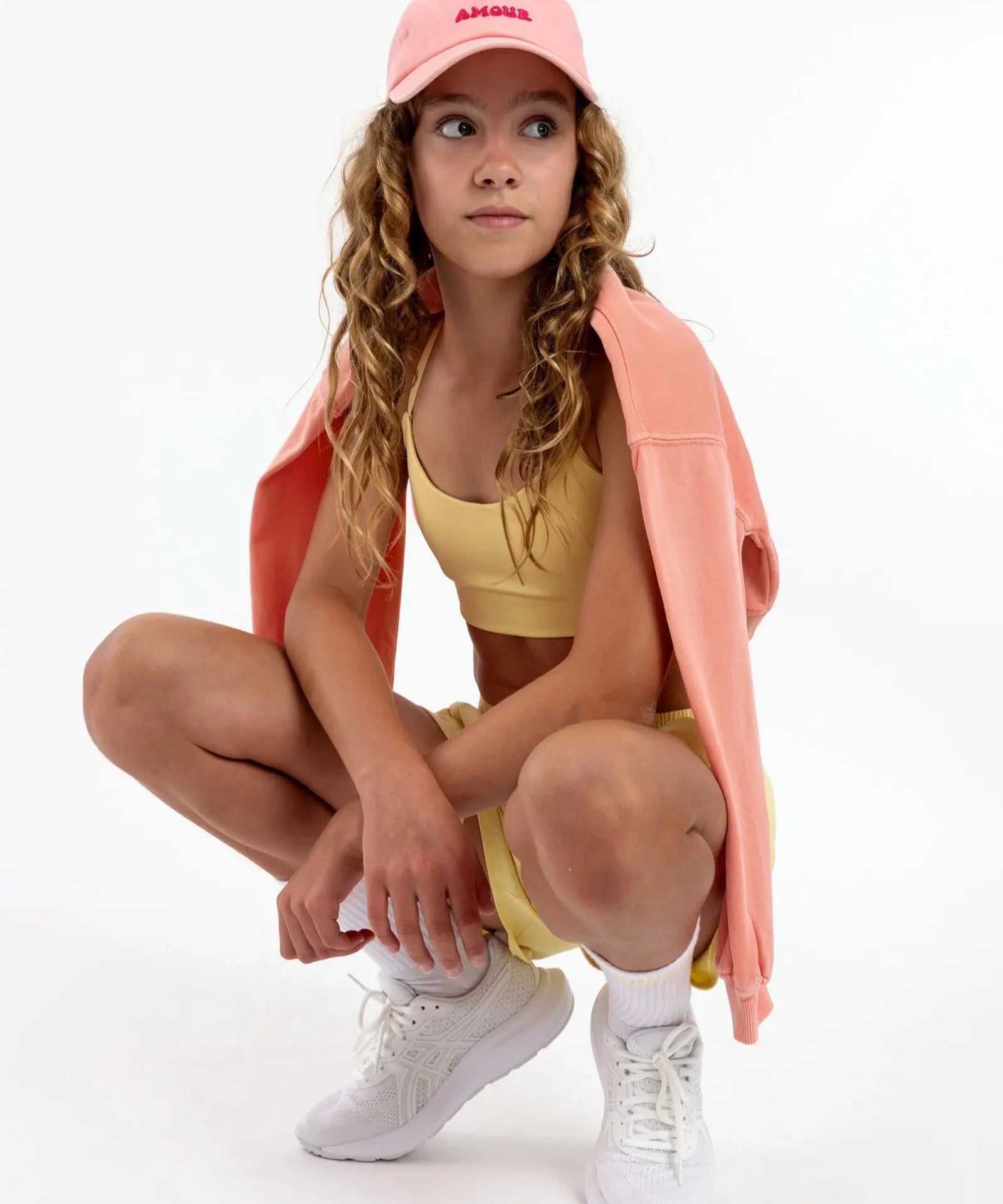 Side view of a girl wearing a yellow first longline sports bra showing smooth scoop neckline and a seamless underband.
