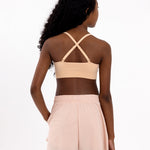 Back view of a girl wearing a beige first training bra showing adjustable crossover straps and seamless underband.