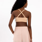 Back view of a girl wearing a beige first training bra showing adjustable crossover straps and seamless underband.