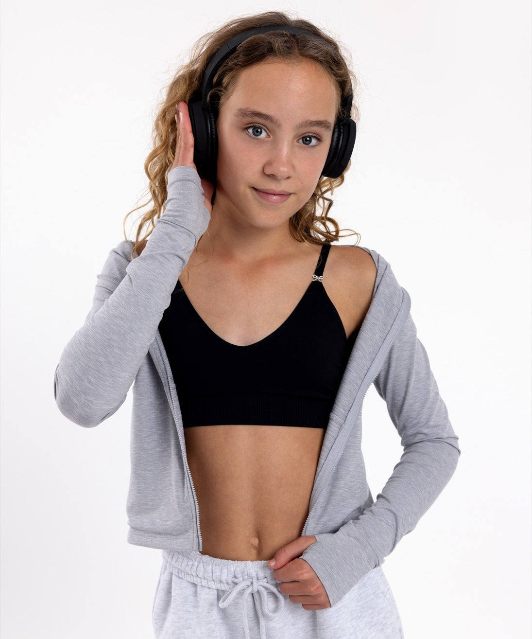 Girl listening to music wearing a black training bra with a seamless underband and adjustable straps.