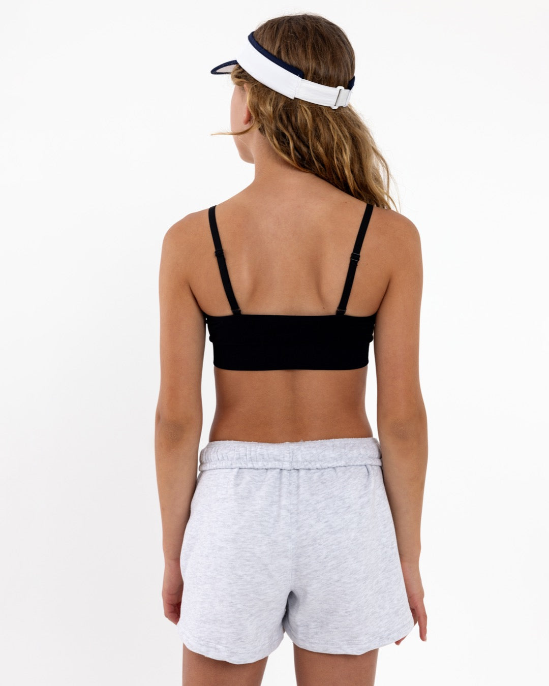 Back view of a girl wearing a black first training bra showing adjustable straps and a seamless crop top fit.