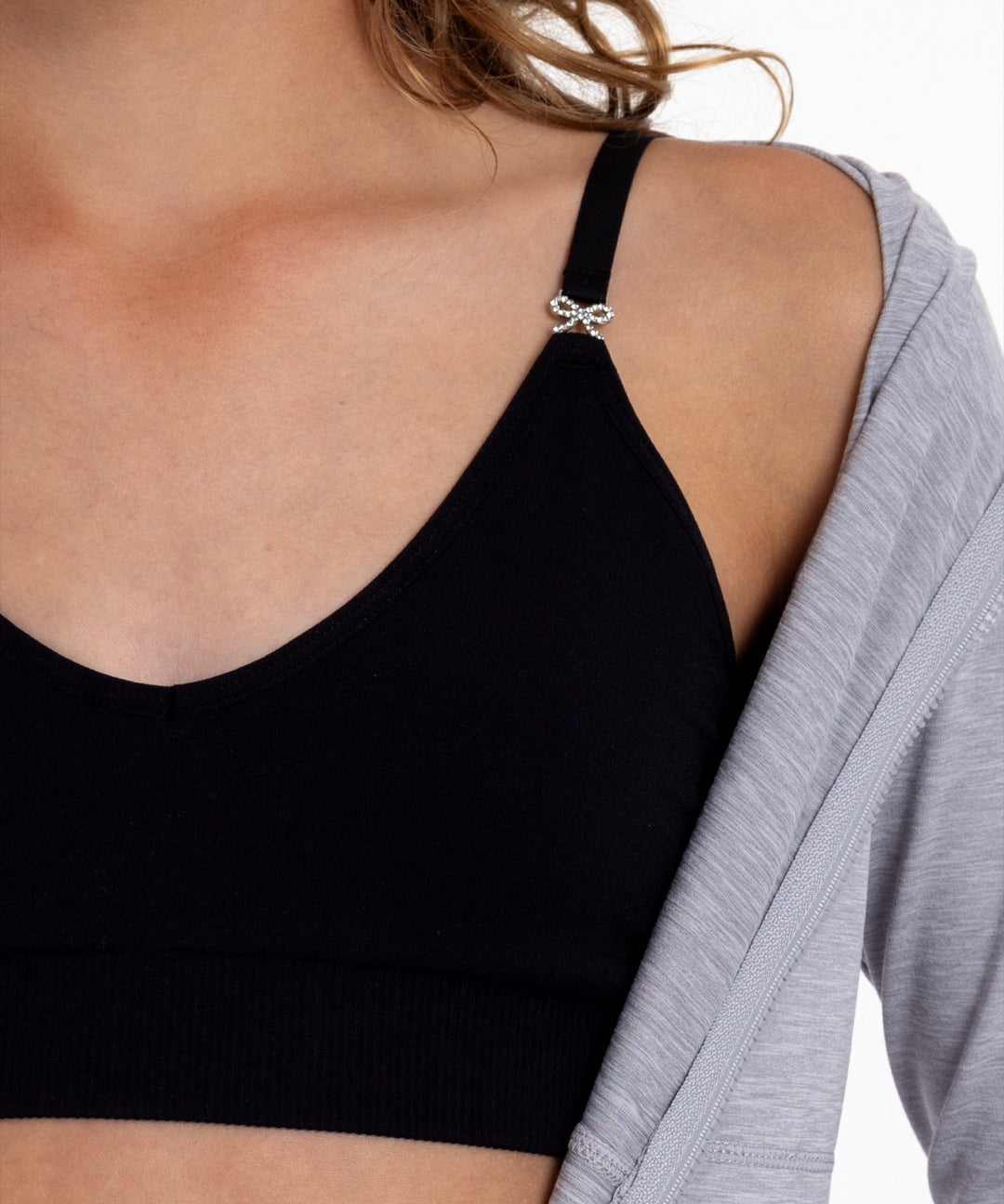 Close-up of a girl wearing a black training bra showing adjustable straps with bow detail and seamless underband.