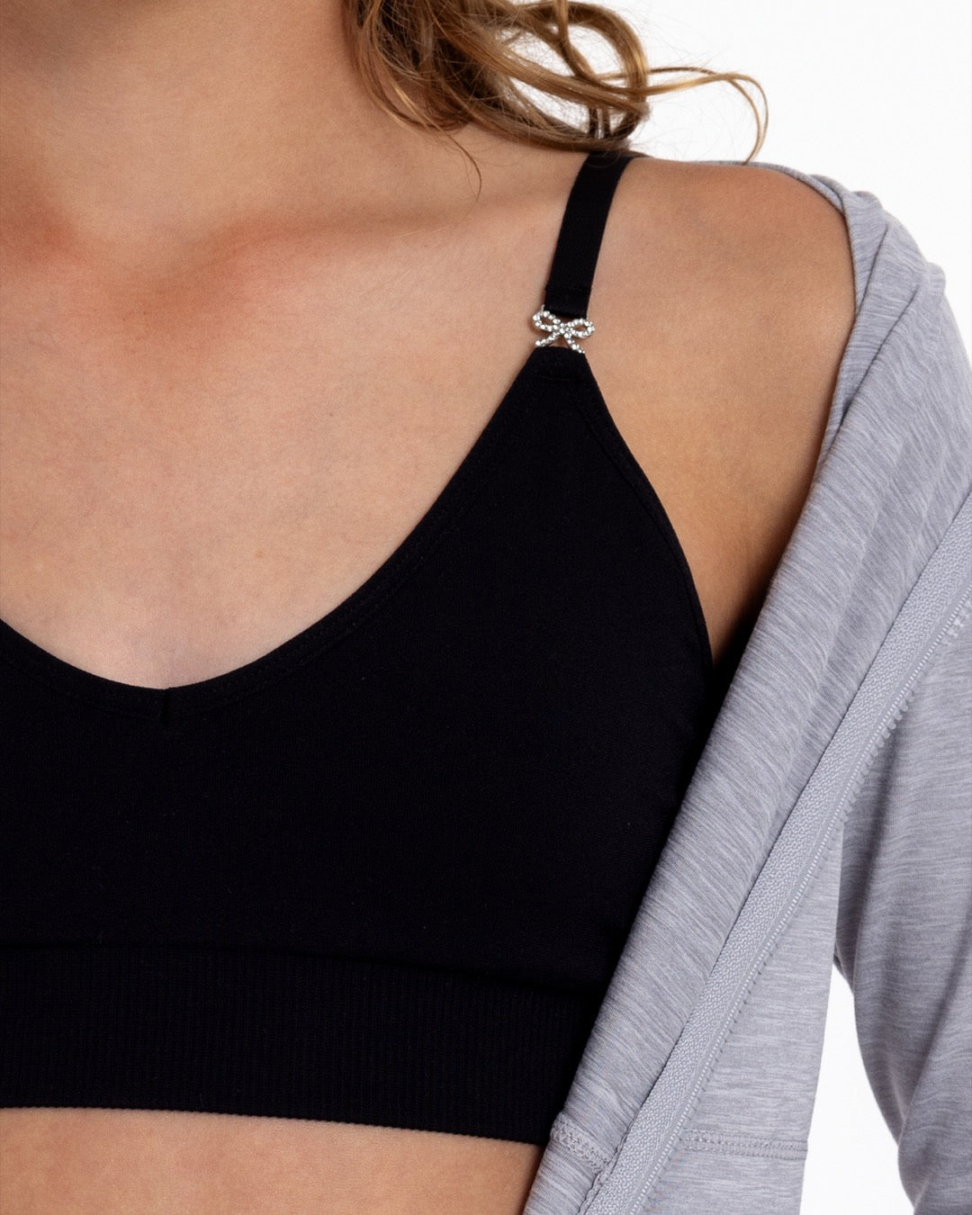 Close-up of a girl wearing a black training bra showing adjustable straps with bow detail and seamless underband.