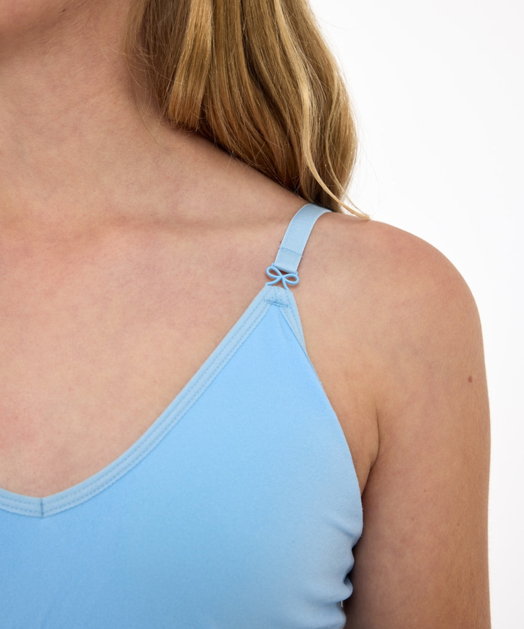 Close-up of a girl wearing a light-blue training bra showing adjustable straps with bow detail and seamless underband.