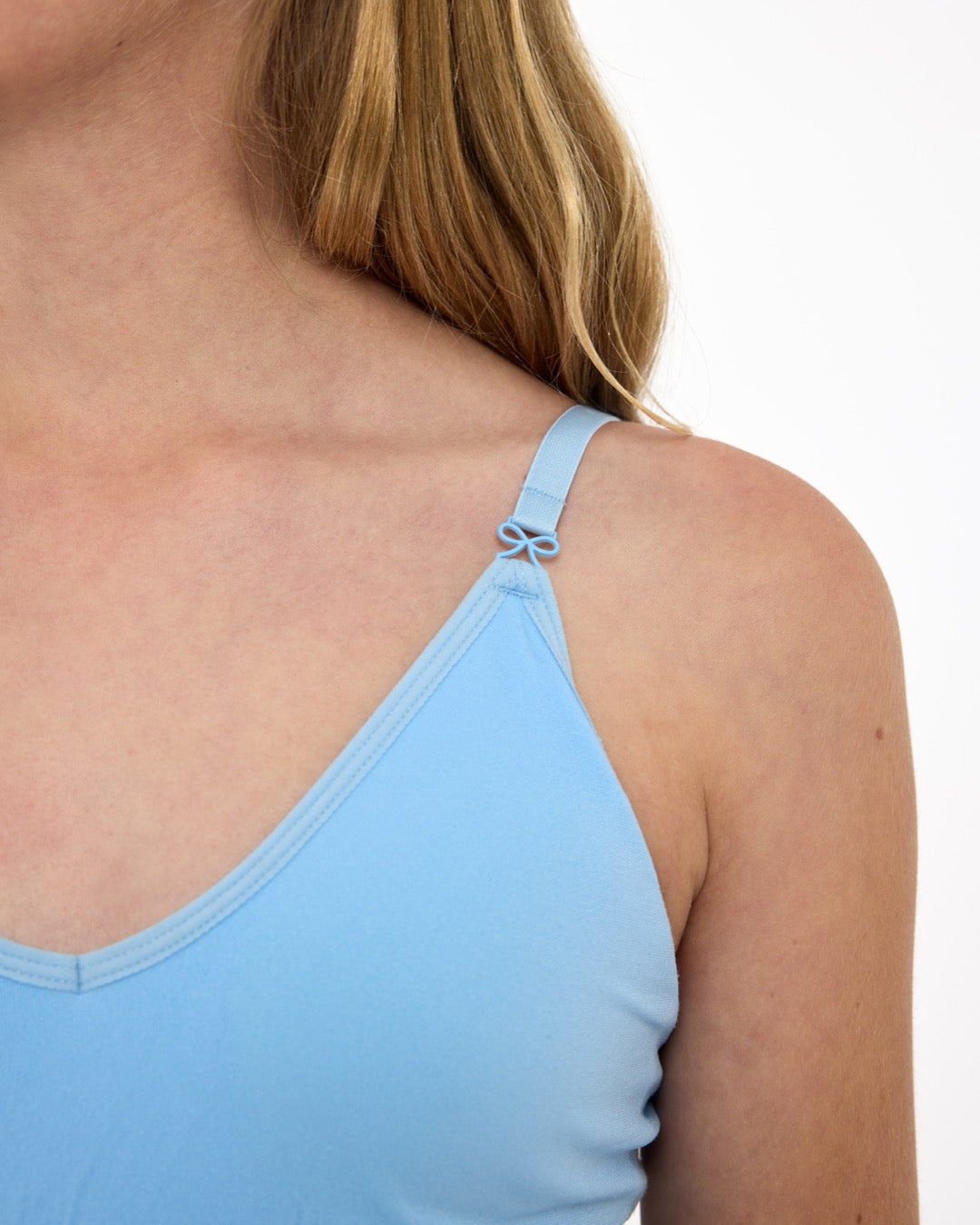 Close-up of a girl wearing a light-blue training bra showing adjustable straps with bow detail and seamless underband.