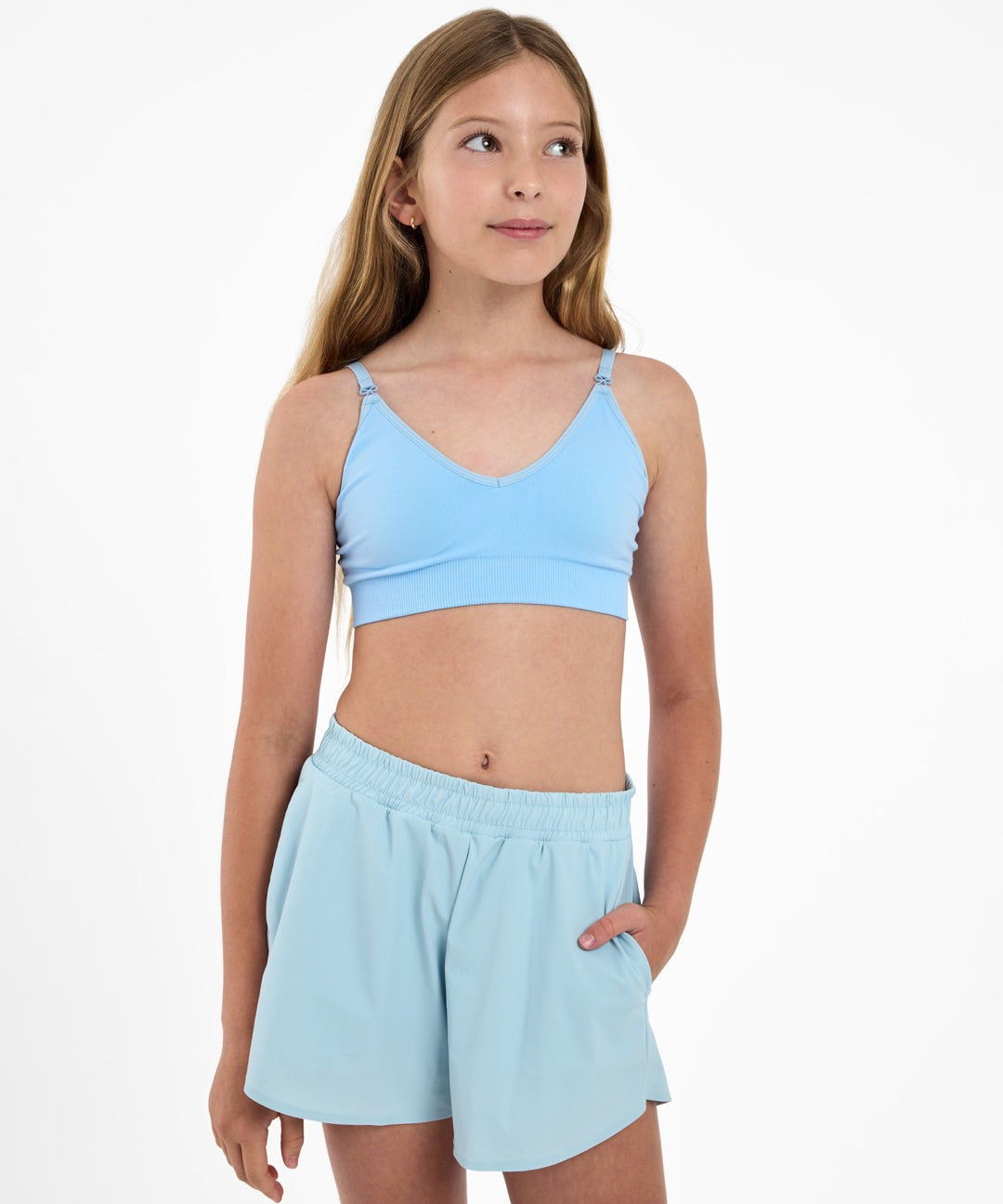 Girl looking up wearing a light-blue seamlessbra and adjustable straps with bow detail.