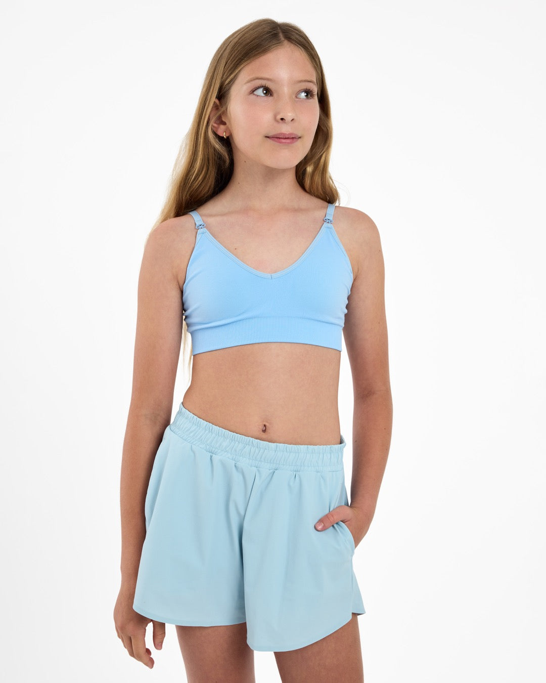 Girl looking up wearing a light-blue seamlessbra and adjustable straps with bow detail.