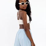 Side view of a girl wearing a white first training bra showing adjustable straps and a seamless crop top fit.